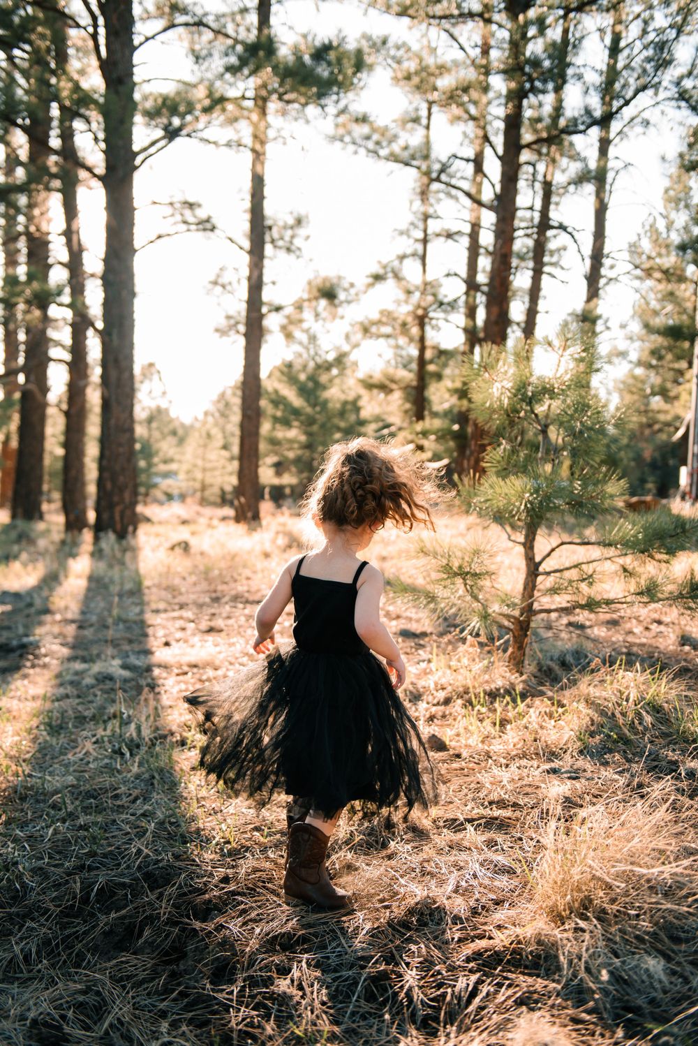 Silhouette of child playing in forest during golden hour.