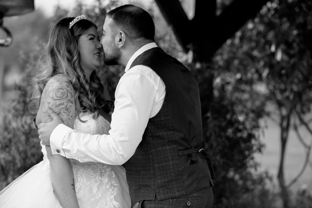 Black and white intimate wedding portrait capturing a tender moment between newlyweds.