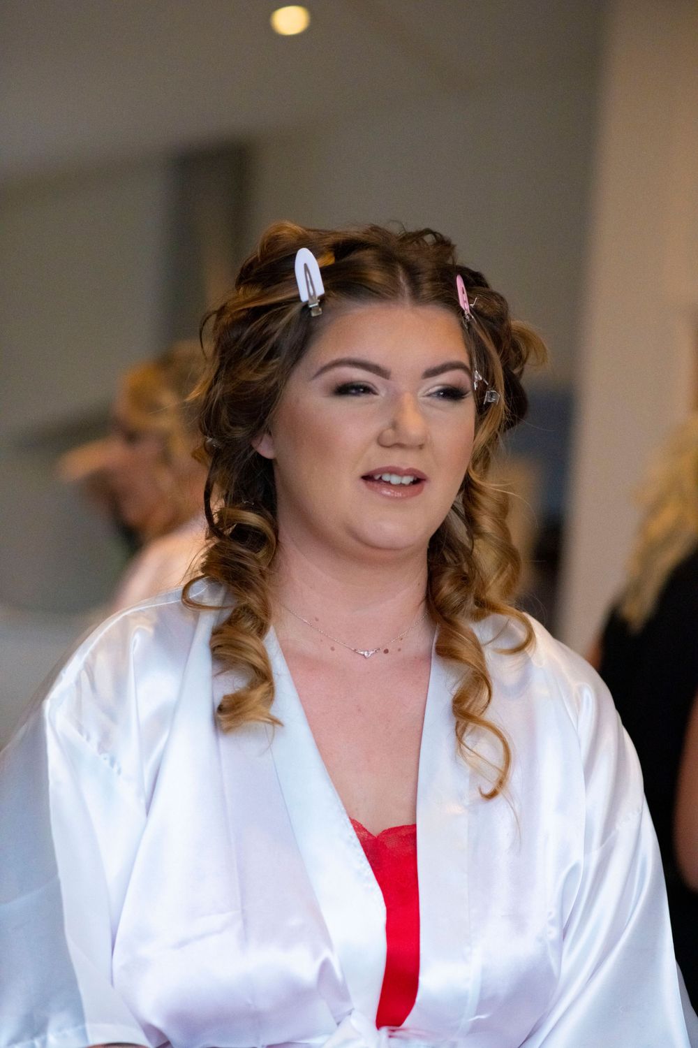 Bride in white robe and red undergarment getting ready for her wedding day.