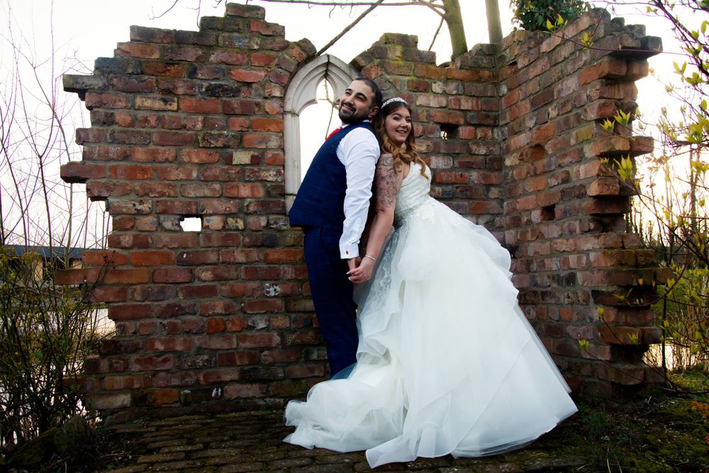 Wedding couple poses against rustic brick wall ruins during their photo session.