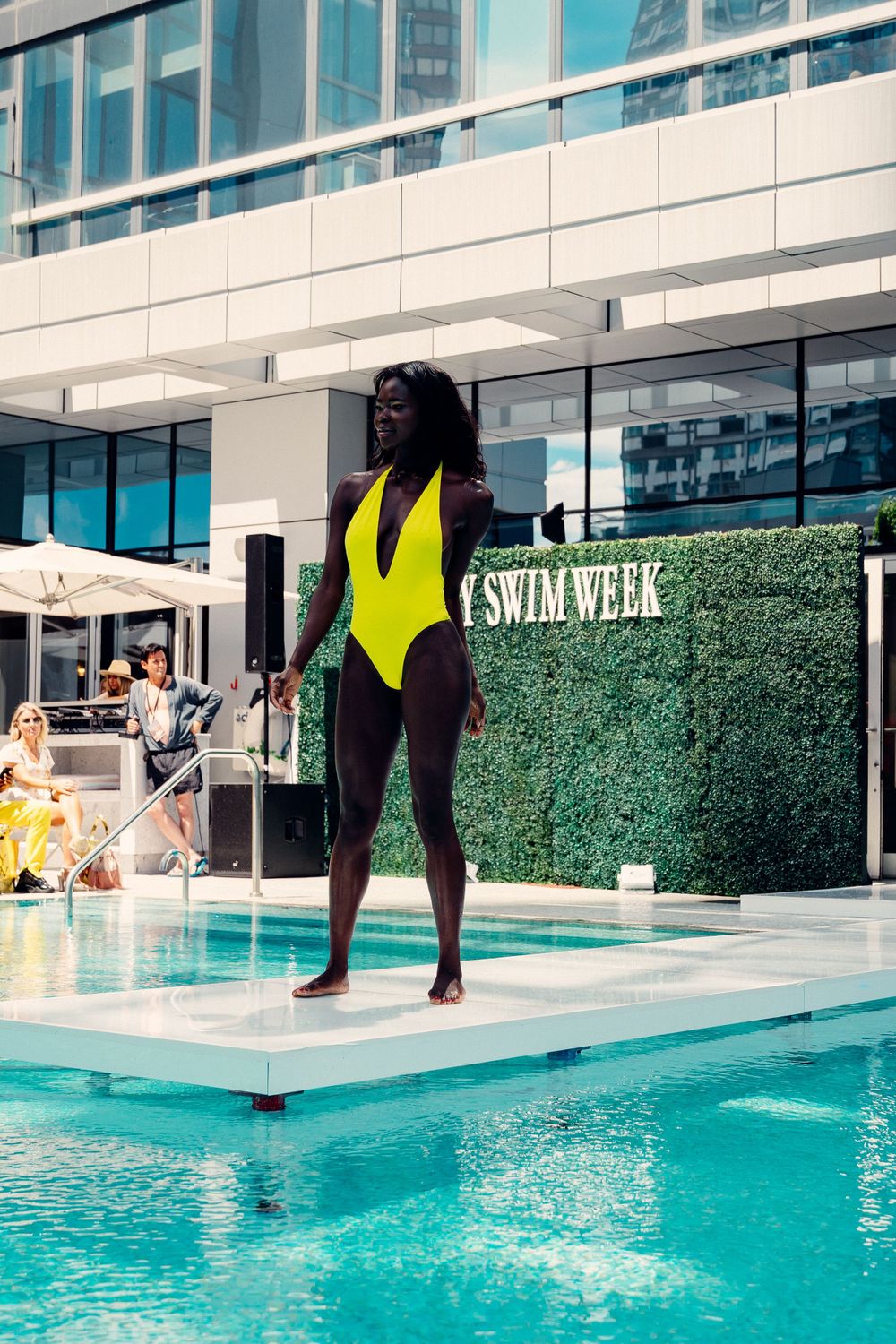 Person in black swimsuit performs athletic dive sequence into turquoise pool at upscale fitness facility.