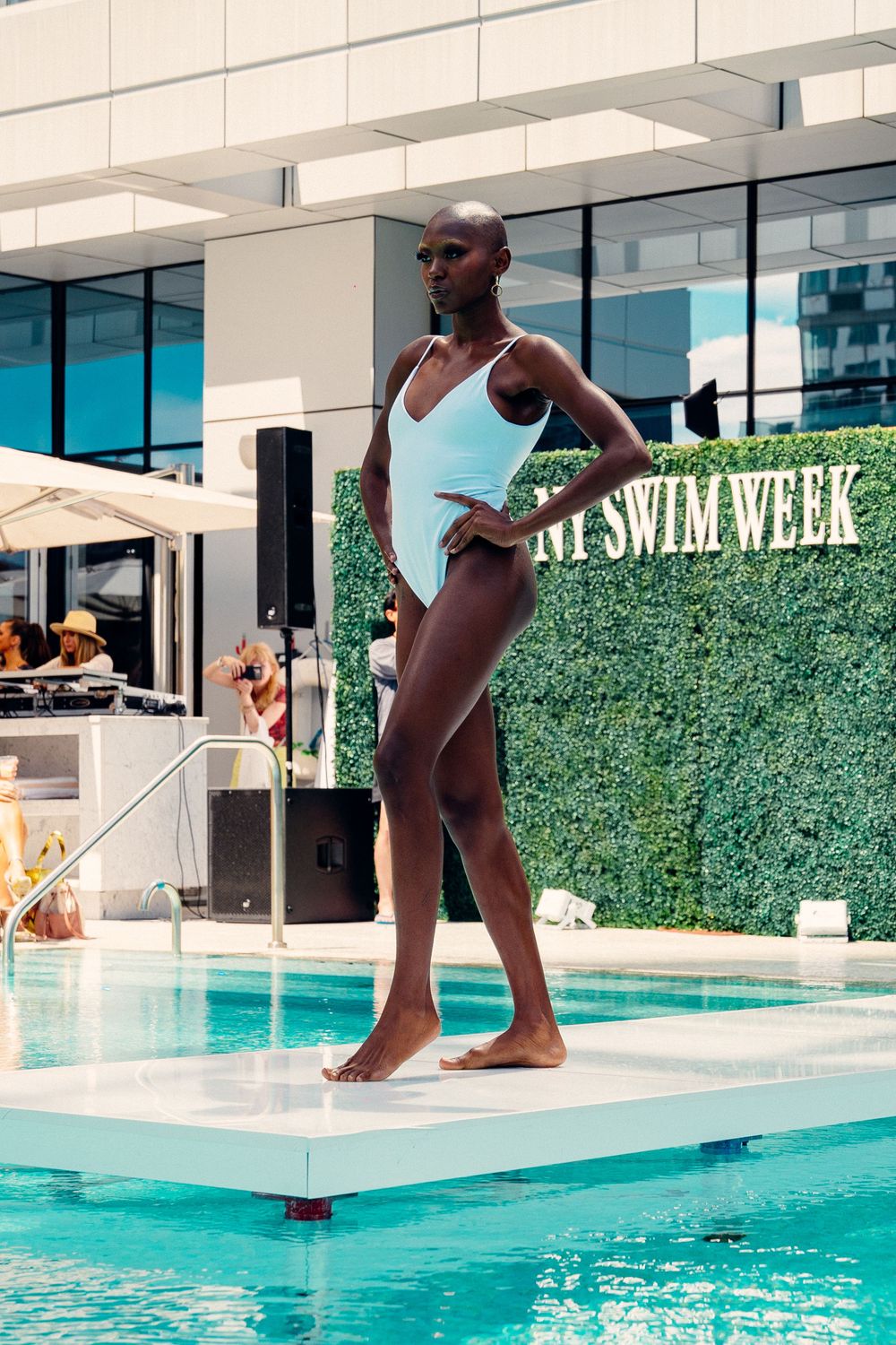 A sequence showing a figure in white swimwear diving gracefully into a turquoise pool at a modern outdoor venue.