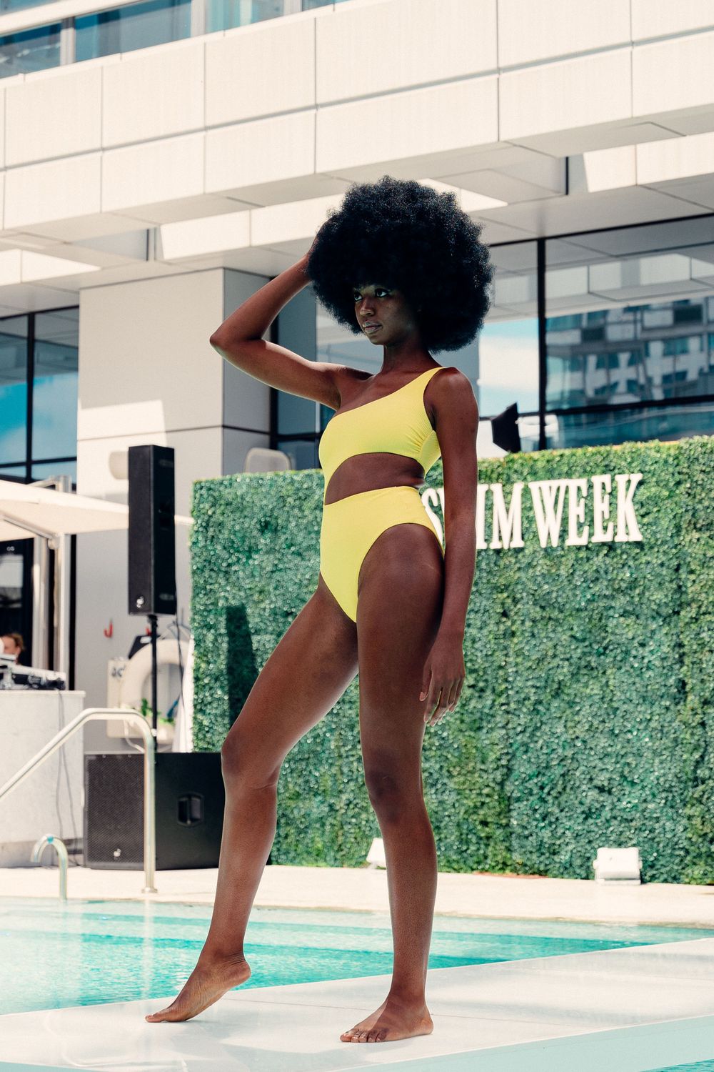 A figure in a yellow swimsuit striking dynamic poses near the edge of an elegant pool.