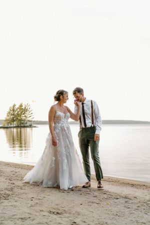 Groom kissing brides hand on the beach during sunset at Northridge Inn, wedding venue