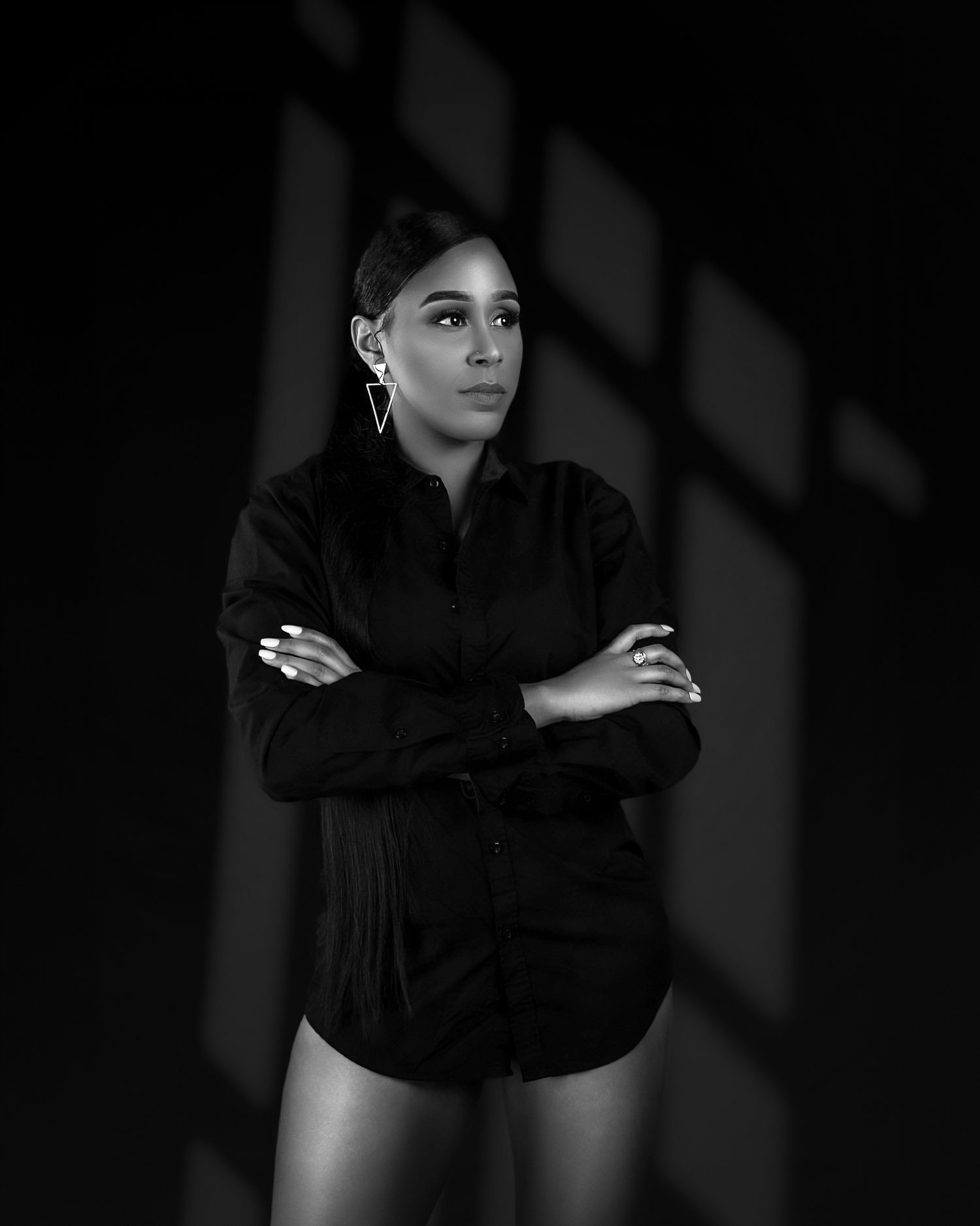 Dramatic black and white portrait with striking window light and shadows.