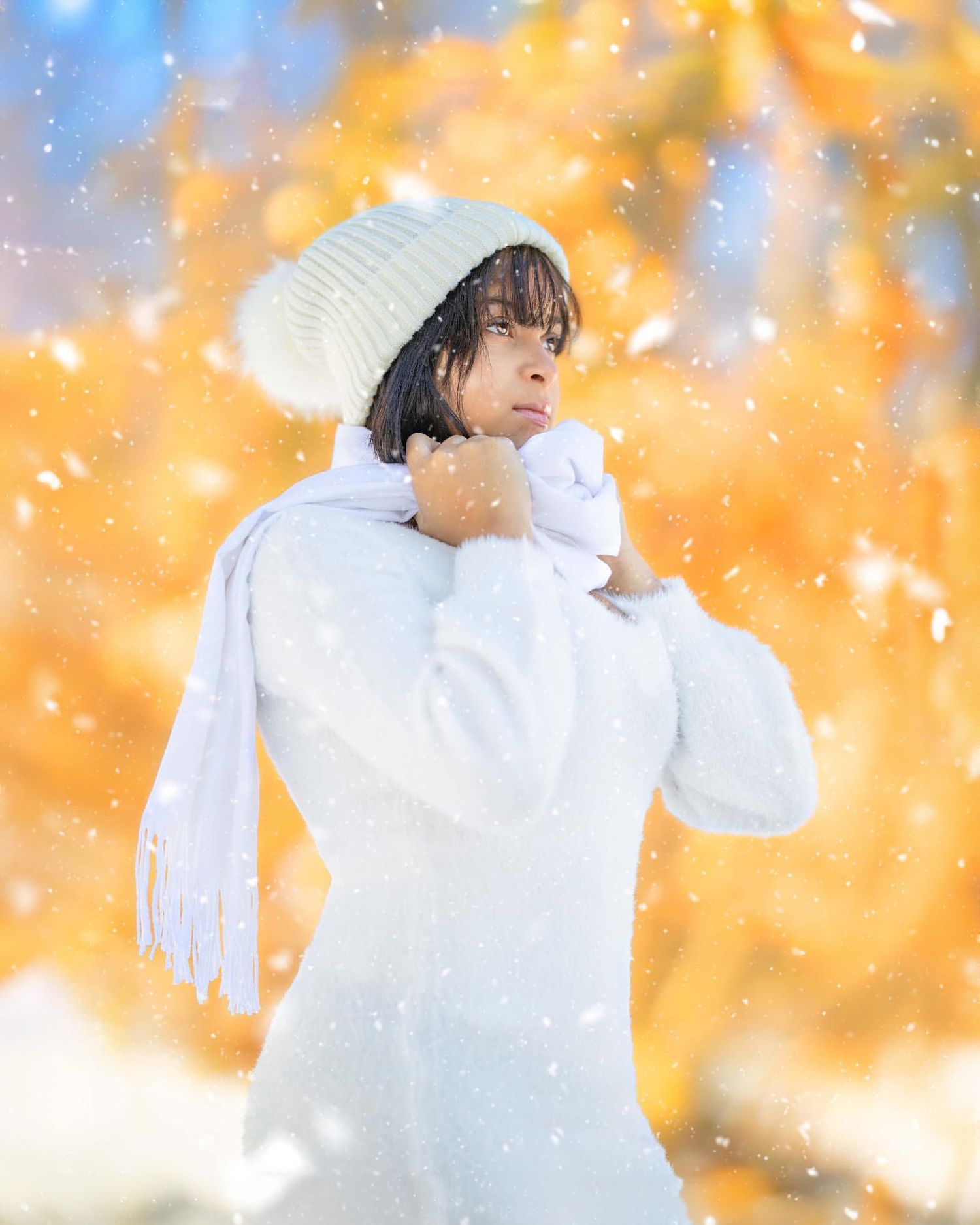 Winter portrait in white knit hat and sweater with snowy bokeh effect in orange lighting.