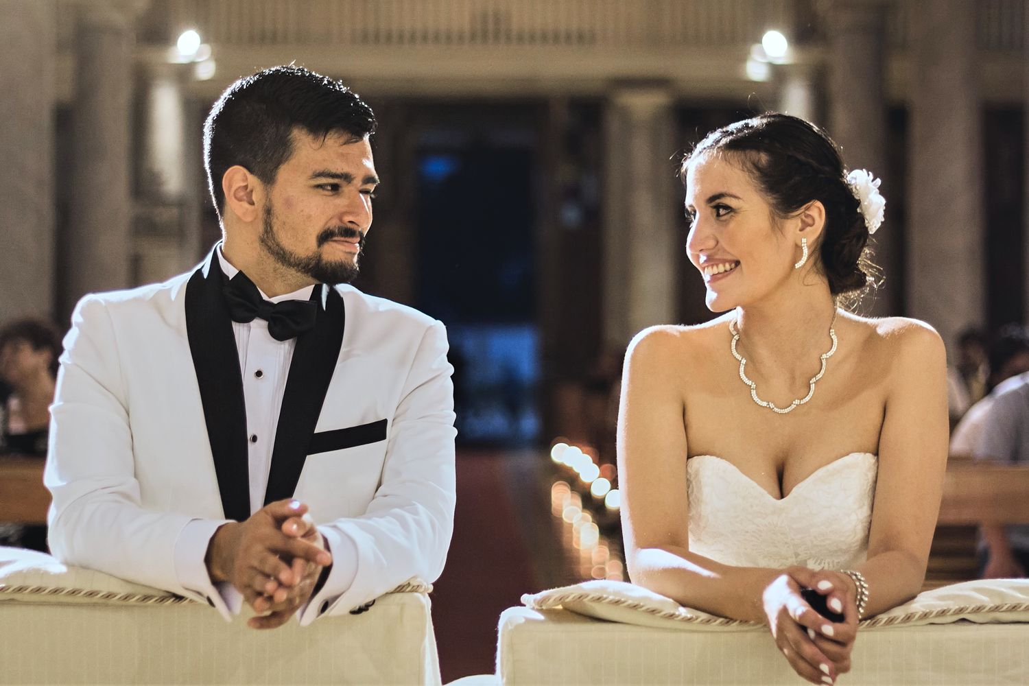 Stylish couple seated in formal attire during their wedding ceremony.