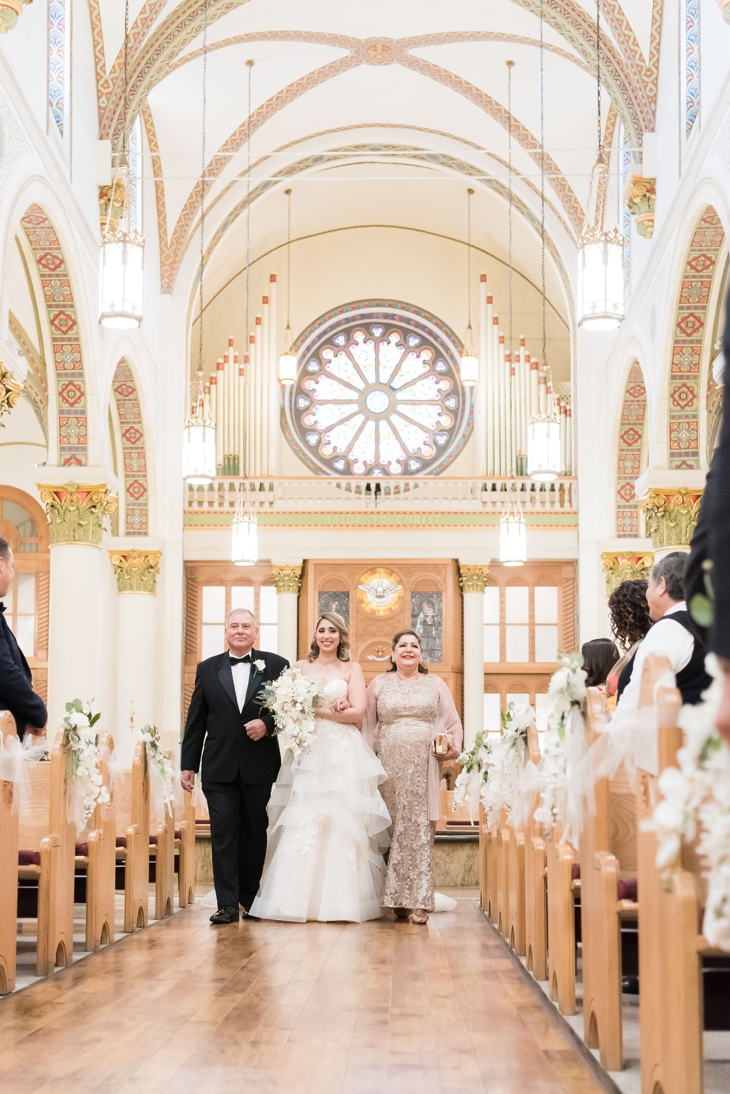 bride walking down the aisle with her parents during church wedding ceremony