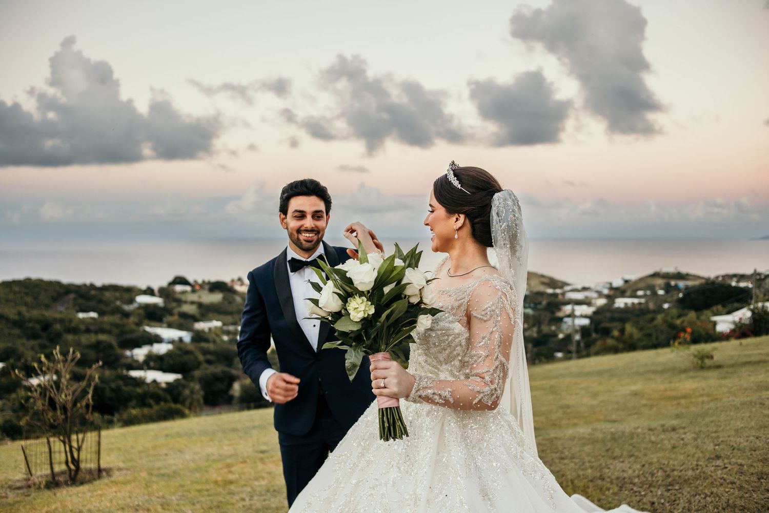 Wedding couple poses against a scenic coastal backdrop during golden hour.