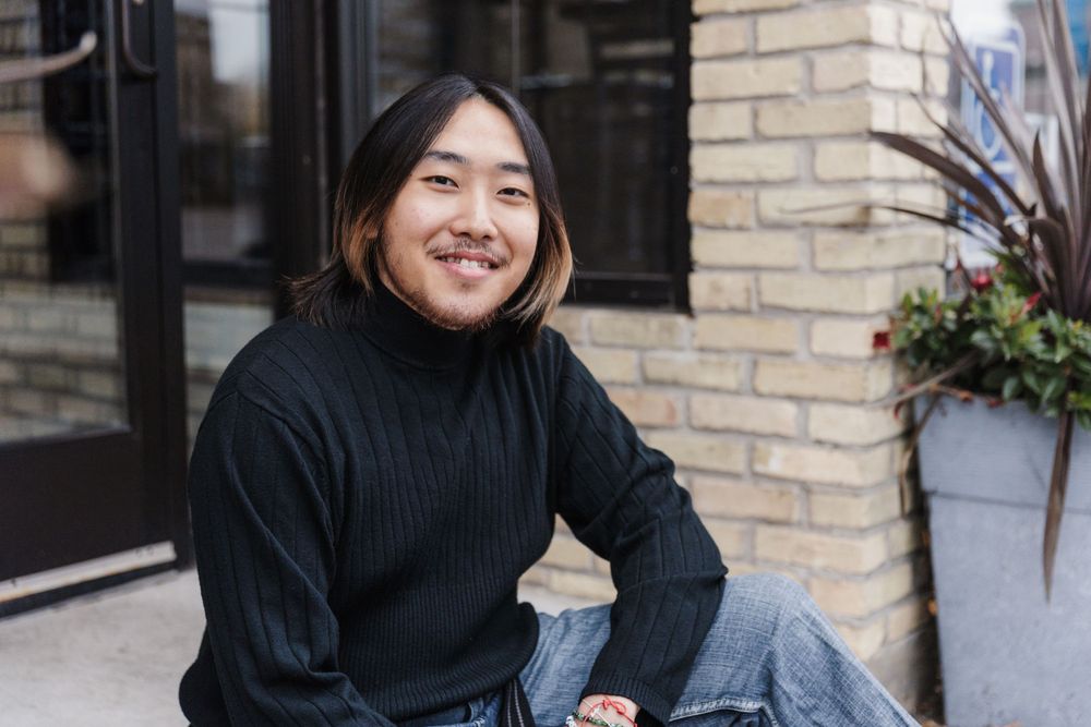 Urban portrait session featuring black turtleneck against brick wall.