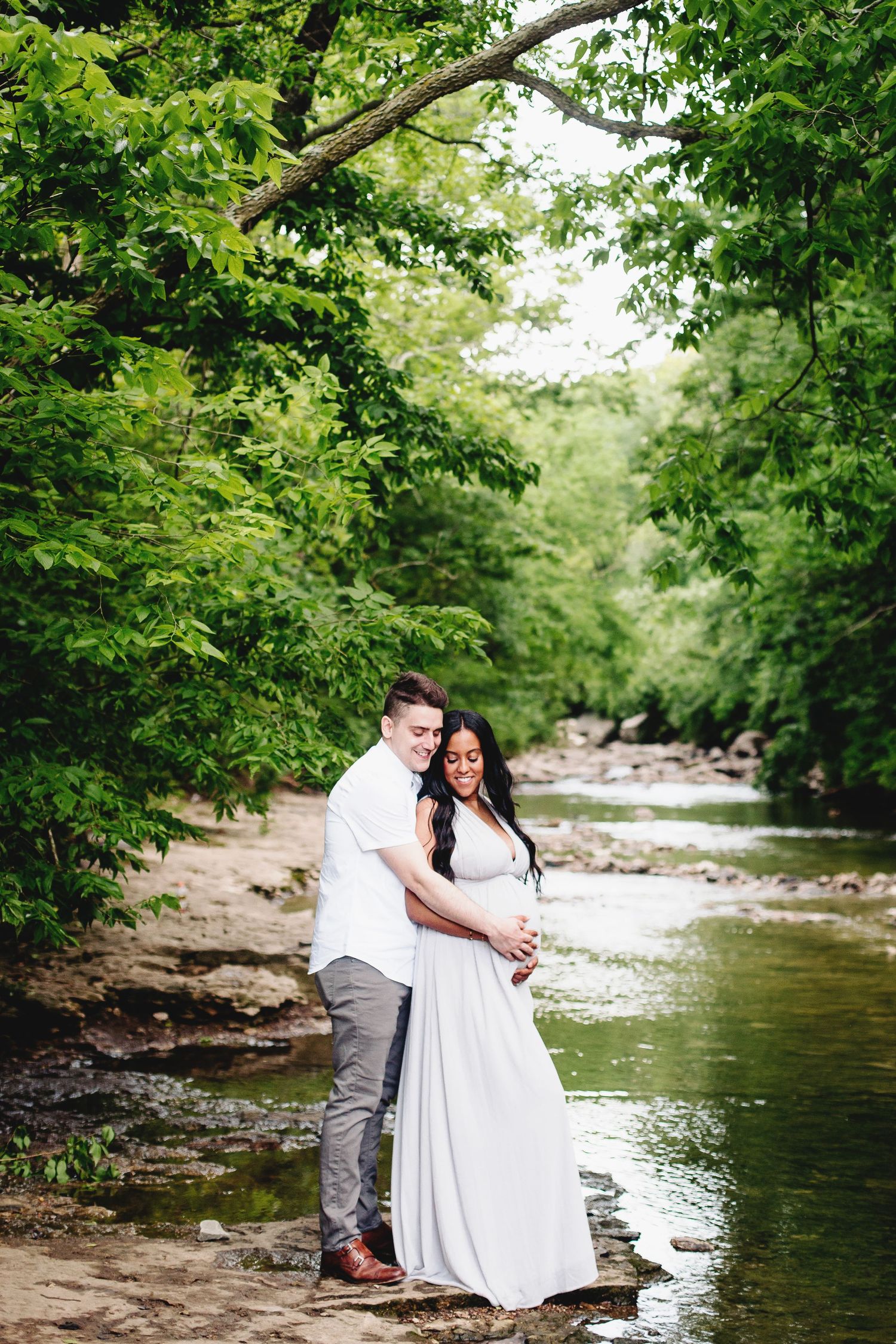 man embracing woman from behind holding her pregnant belly