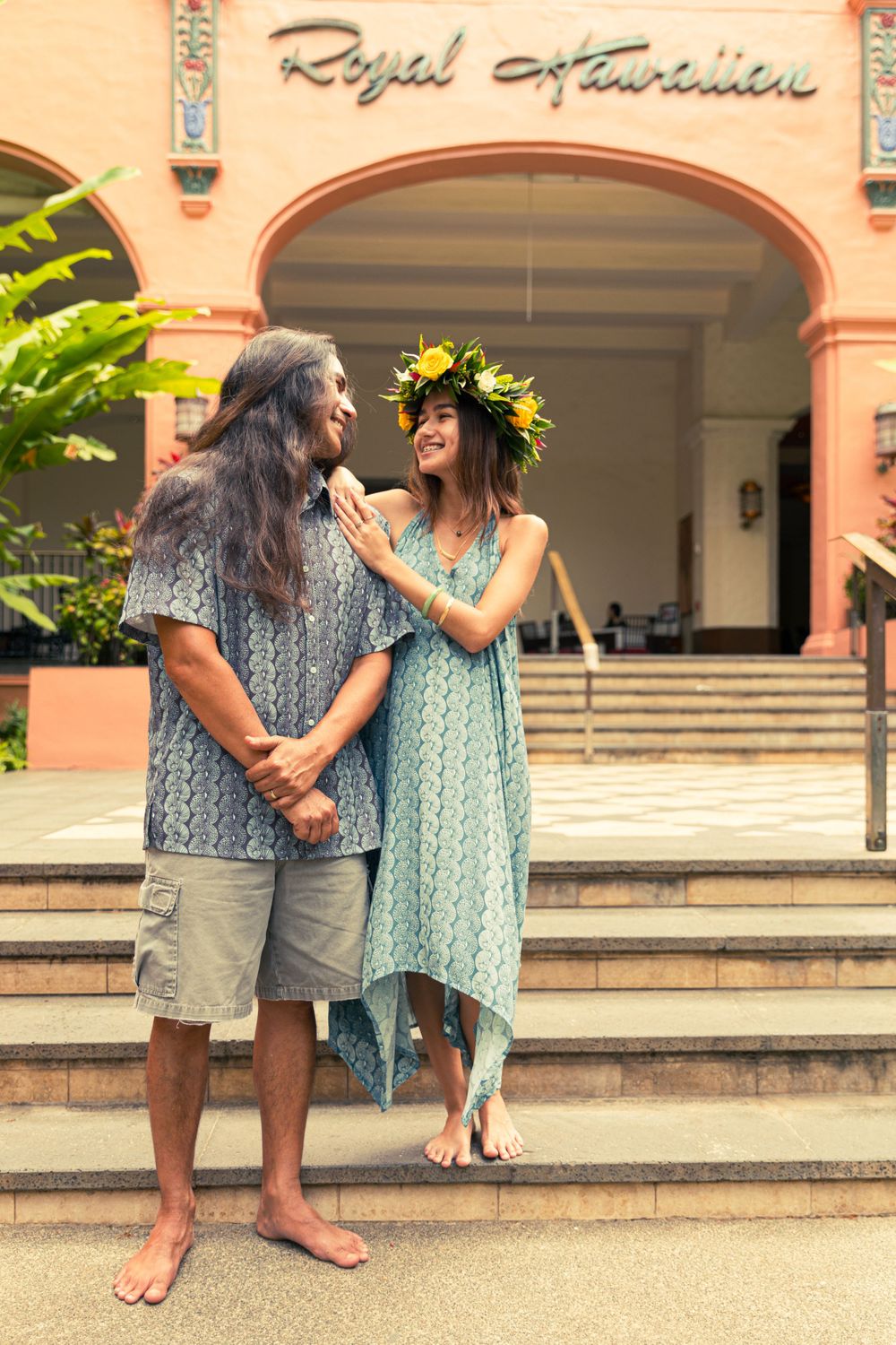 Couple in coordinated outfits sharing a tender moment outside the Royal Hawaiian building.