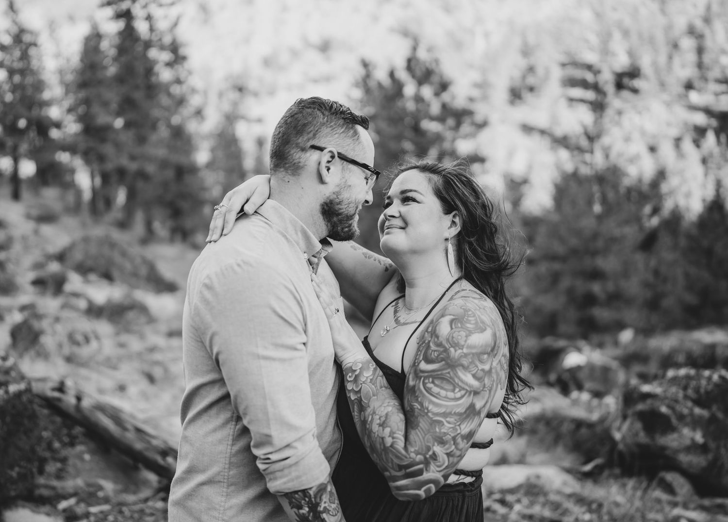 Intimate black and white portrait of couple sharing tender moment against mountain backdrop.