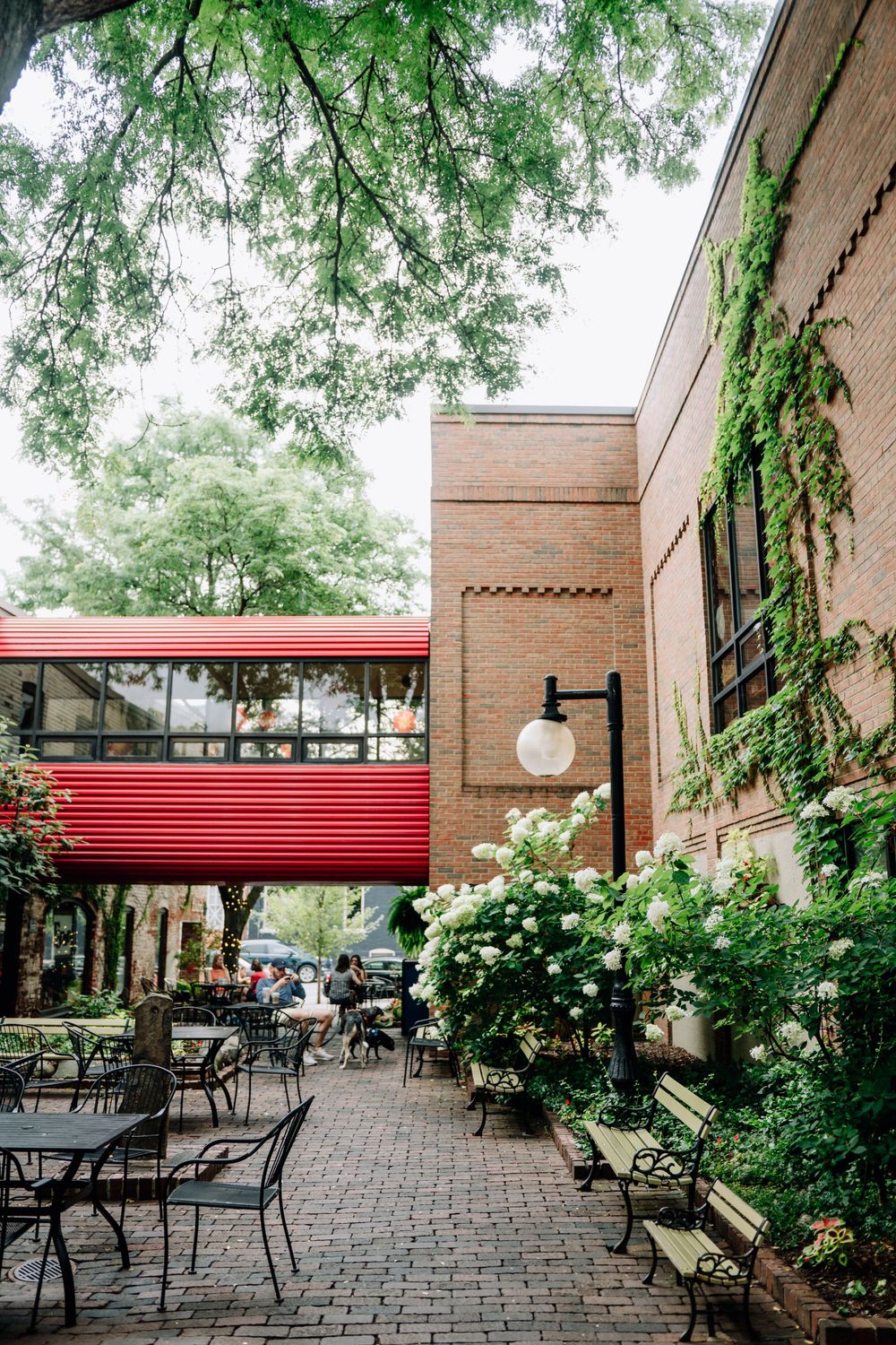 Peaceful outdoor patio area with brick walls, greenery and metal furniture.