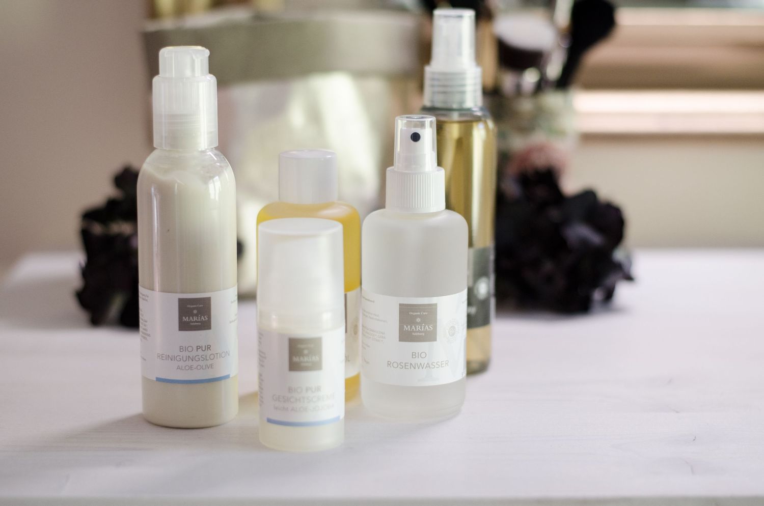 White skincare bottles and beauty products displayed in natural window light.