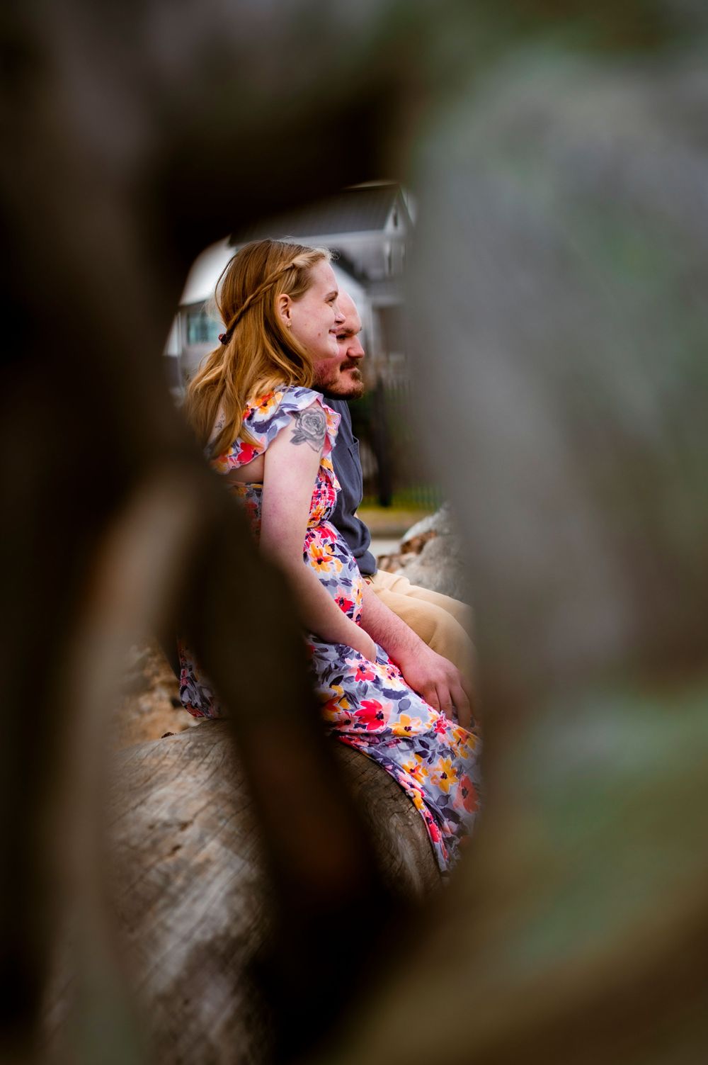 Person in floral dress photographed through natural framing of trees and leaves.