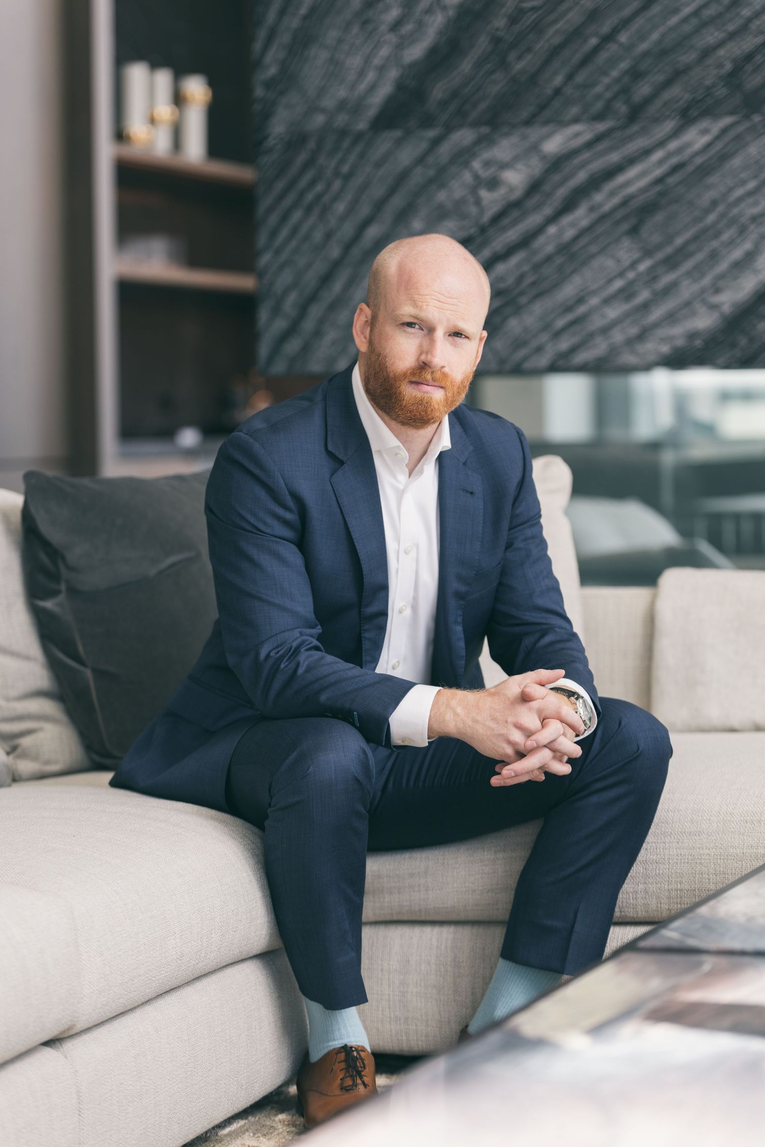 Realtor sitting on couch in a suit looking towards the camera
