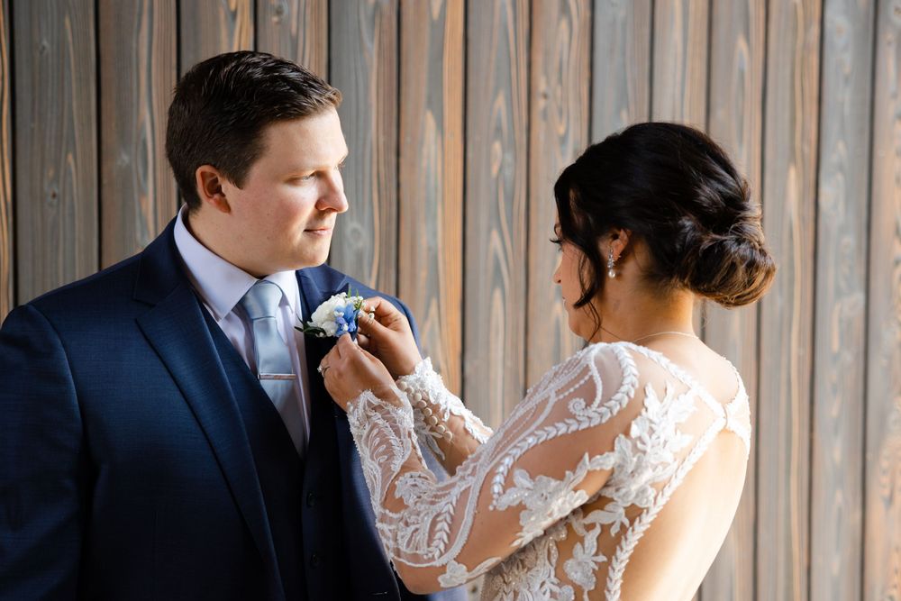 Bride adjusts groom's boutonniere before wedding ceremony at Jorgensen Farms in Westerville, Ohio.