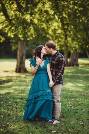 Couple sharing tender moment on grassy hill in autumn setting.