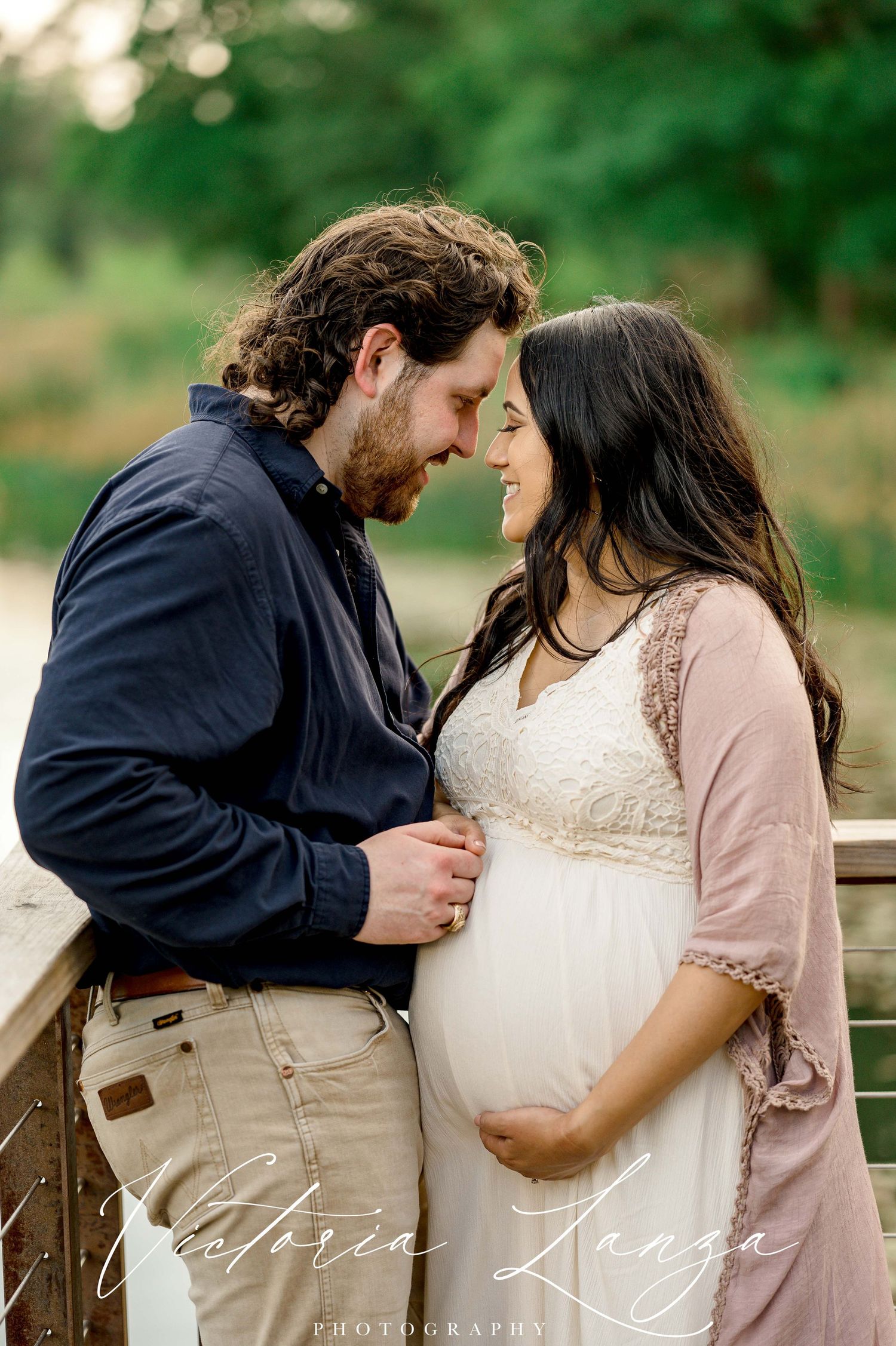 intimate maternity photo with husband embracing pregnant wife overlooking a pond and trees in houston