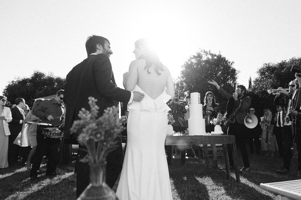 A black and white photo of a wedding couple with musicians performing in the background.