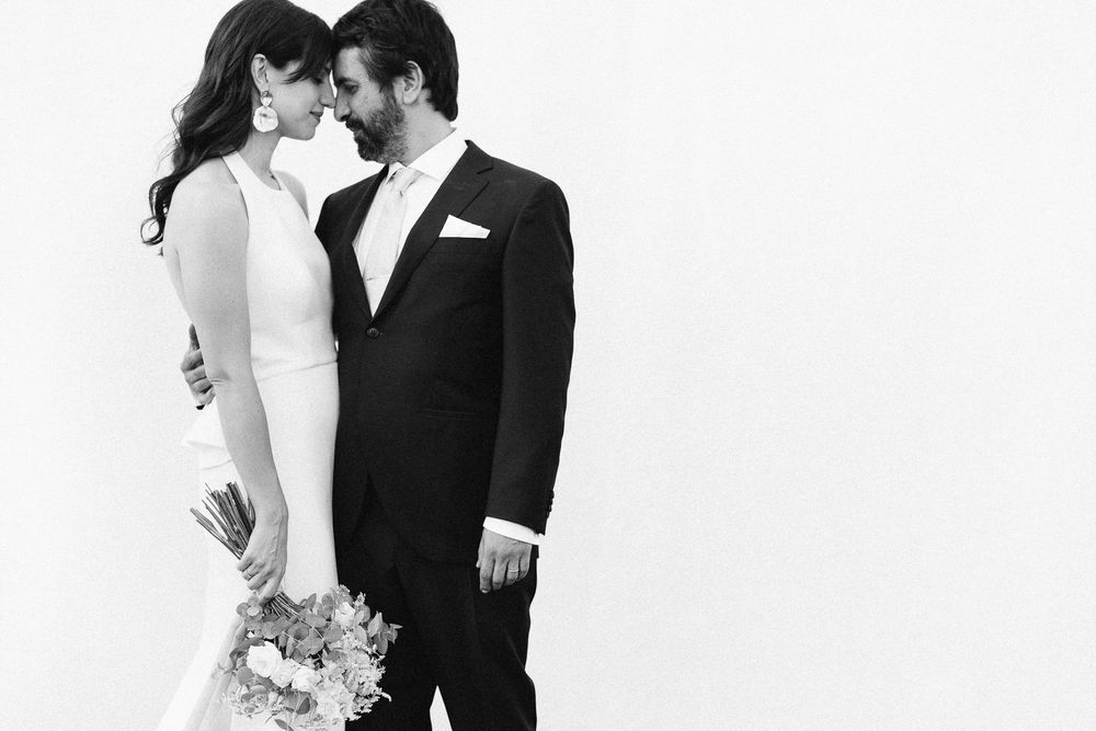 An intimate black and white portrait of newlyweds against a white background.