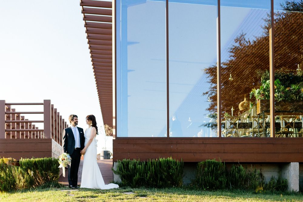 Modern architectural wedding venue with glass walls and wooden beams.