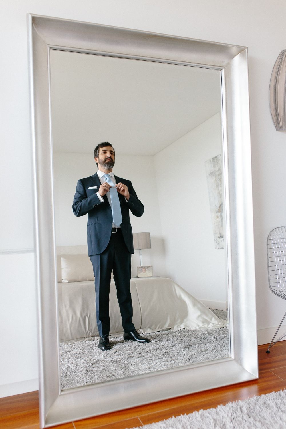 Mirror reflection of formal attire preparation in minimalist white room.