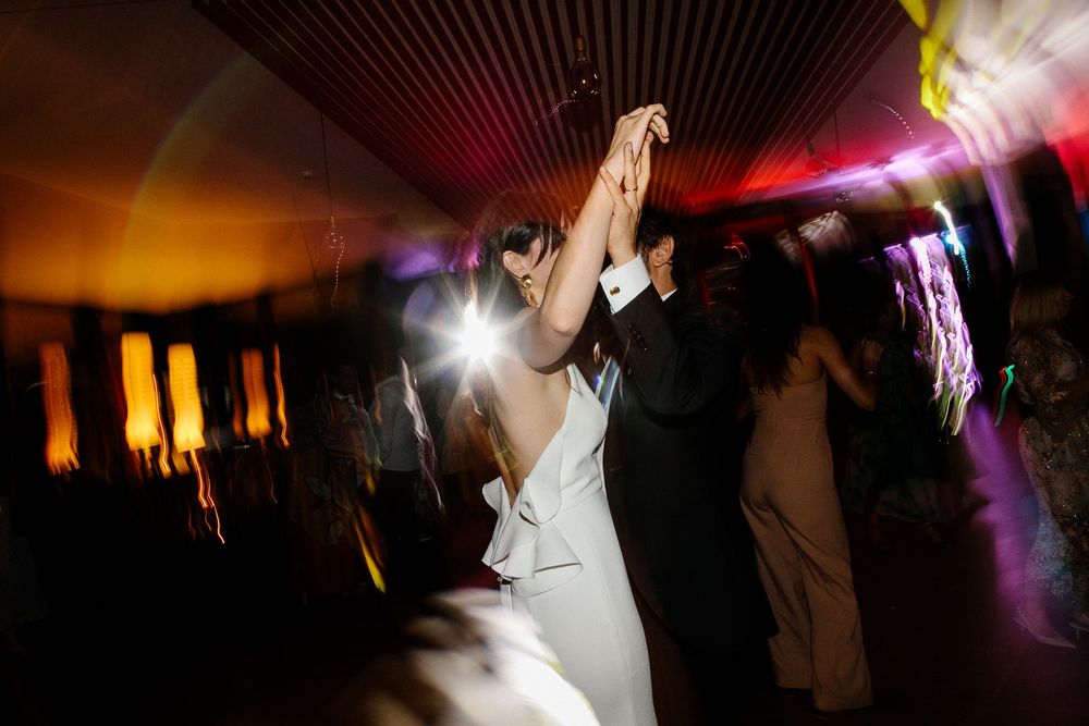 Dancing at a wedding reception with dramatic orange and purple lighting effects.