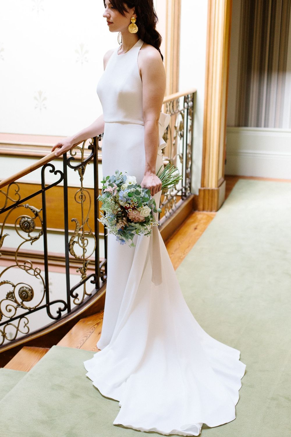 Stunning minimalist wedding dress with clean lines and flowing train on an elegant staircase.