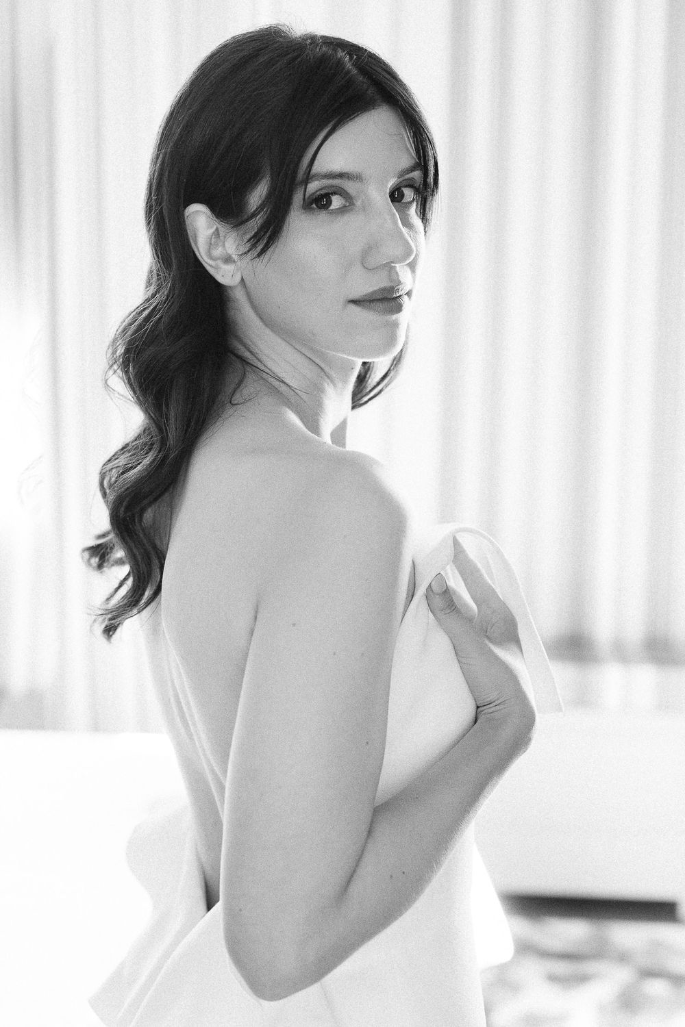 An elegant bridal portrait in black and white showing a sleeveless white gown.