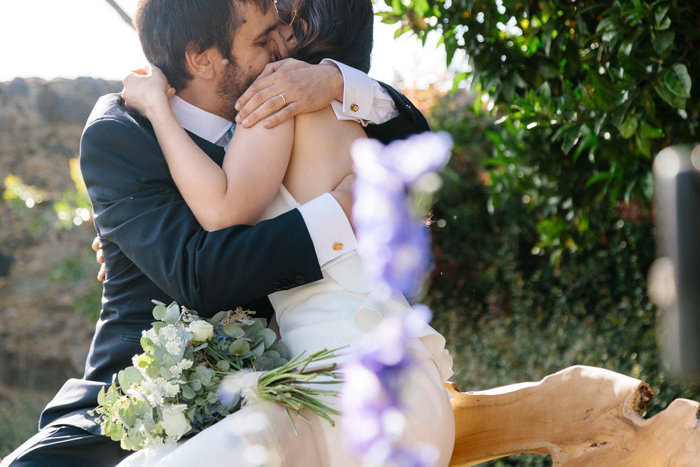 An intimate wedding moment captured among blooming flowers and greenery.