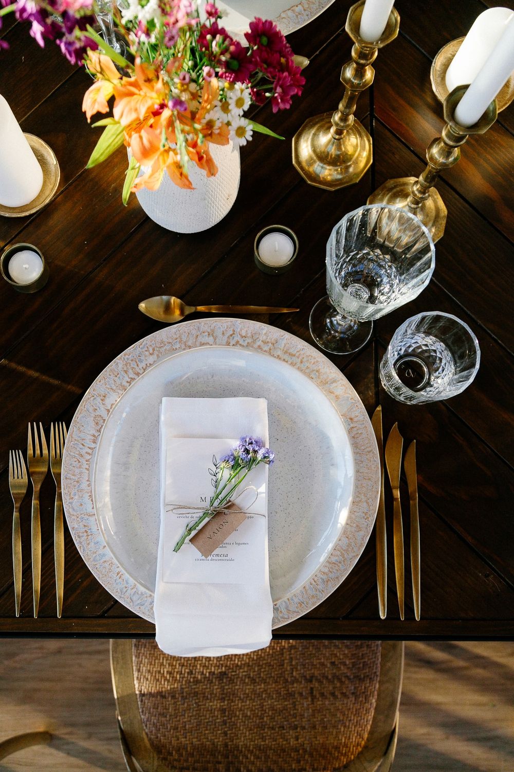 Elegant place setting with gold cutlery, floral centerpiece, and delicate table decor.