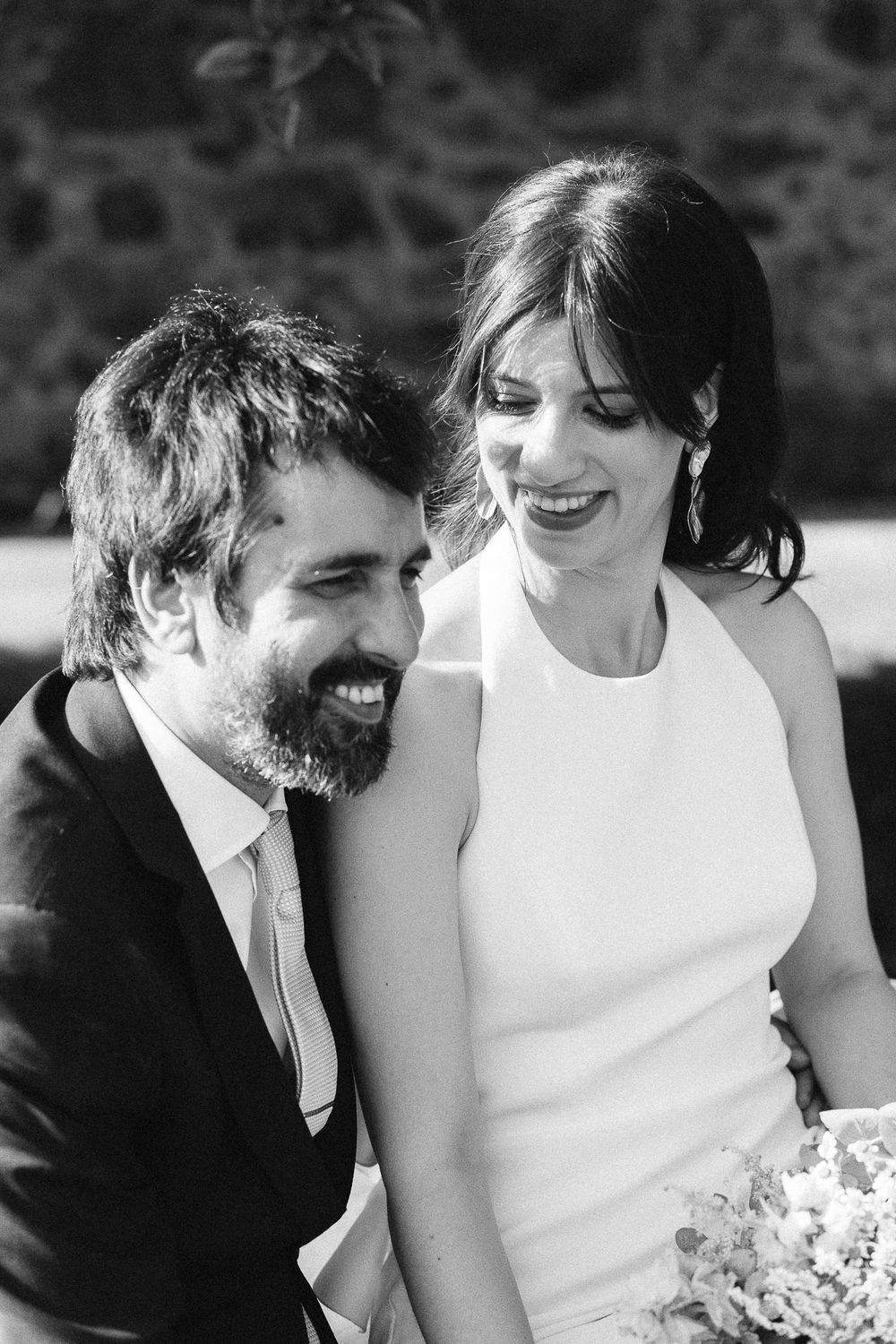 Black and white portrait of a smiling couple in wedding attire with elegant minimalist styling.