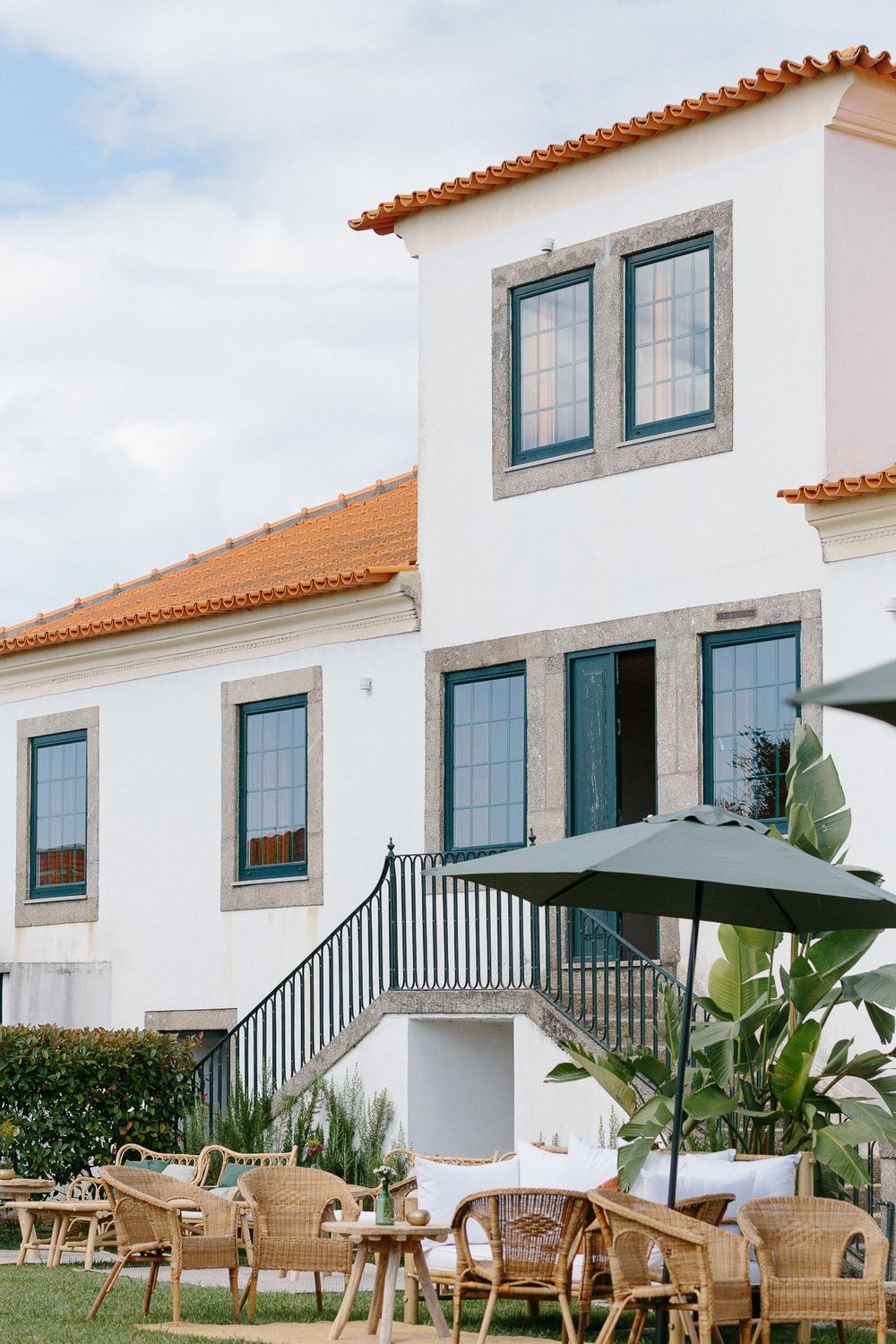 Mediterranean-style white villa with blue windows and outdoor seating area.