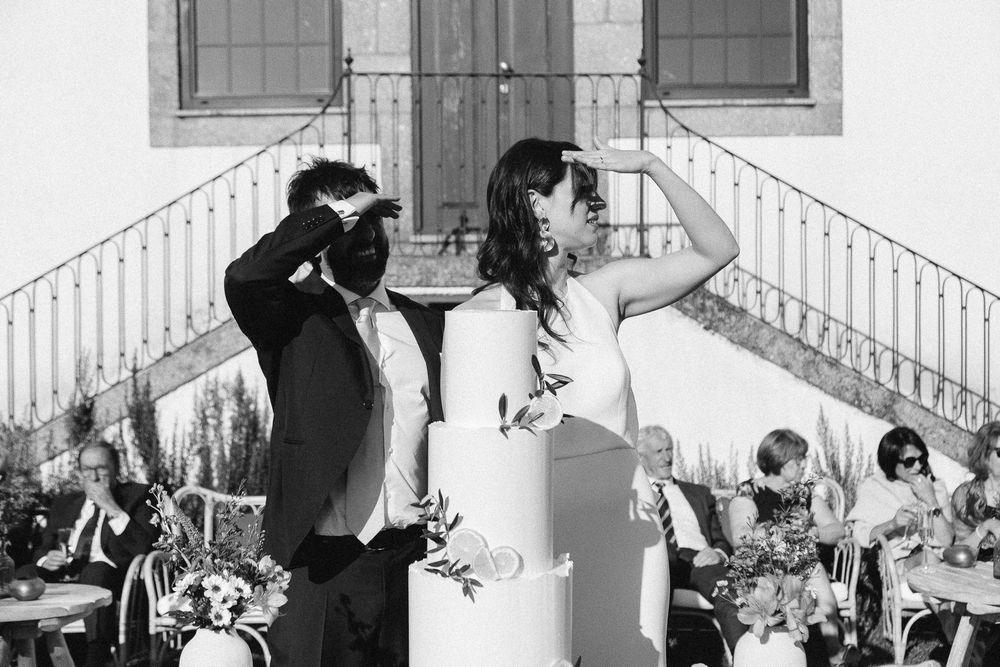 A celebratory moment during an outdoor wedding reception with white architecture in the background.