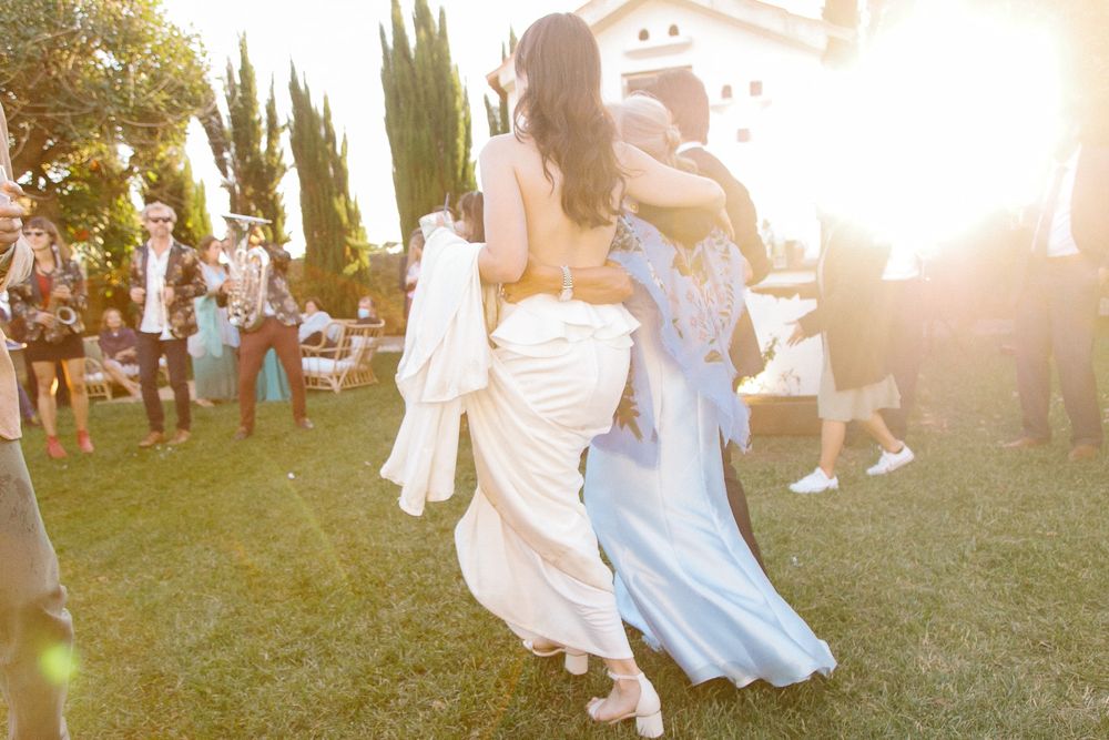 Two people dance together during a sunset garden party with warm golden light.