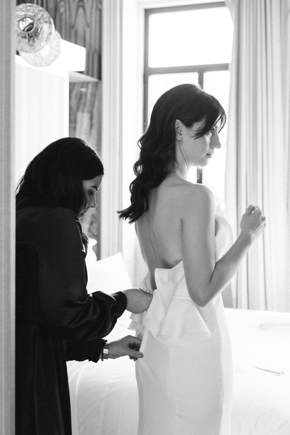 Black and white photo of wedding dress preparations in an elegant room.