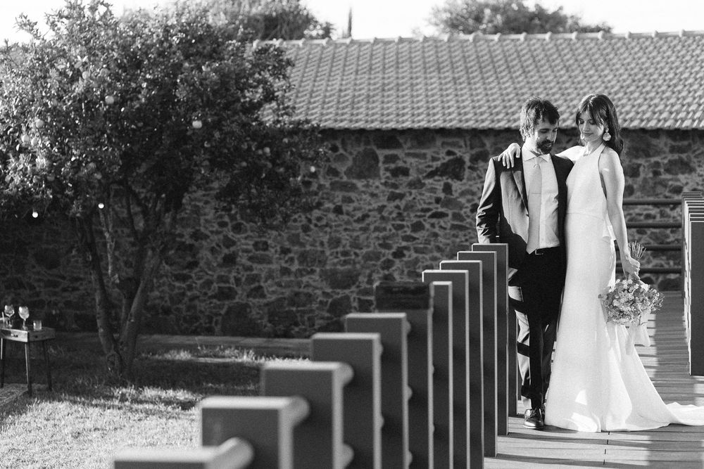 Wedding couple walking along a stone wall pathway in black and white.