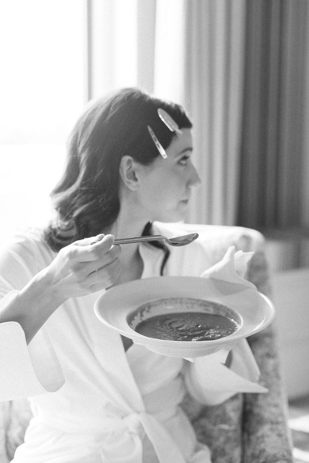 Classic black and white photo showing someone eating soup in a white robe.