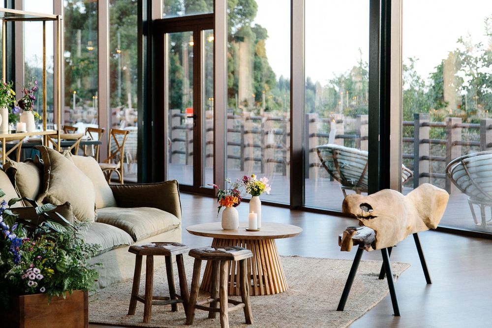 Modern seating area with plush chairs, round accent tables and large windows overlooking an outdoor space.