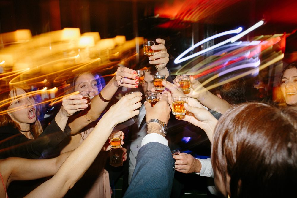 Wedding guests raise their glasses in a celebratory toast with dynamic lighting effects.