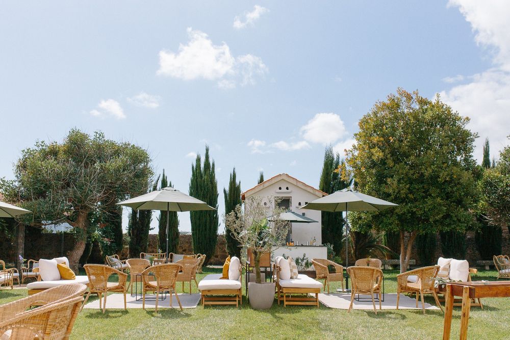 Elegant outdoor wedding venue setup with wooden chairs and umbrellas in a garden setting.