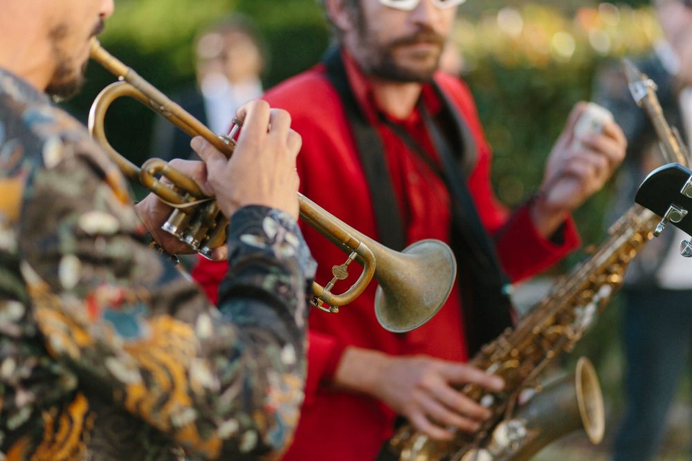 Musicians playing brass instruments during an outdoor performance.