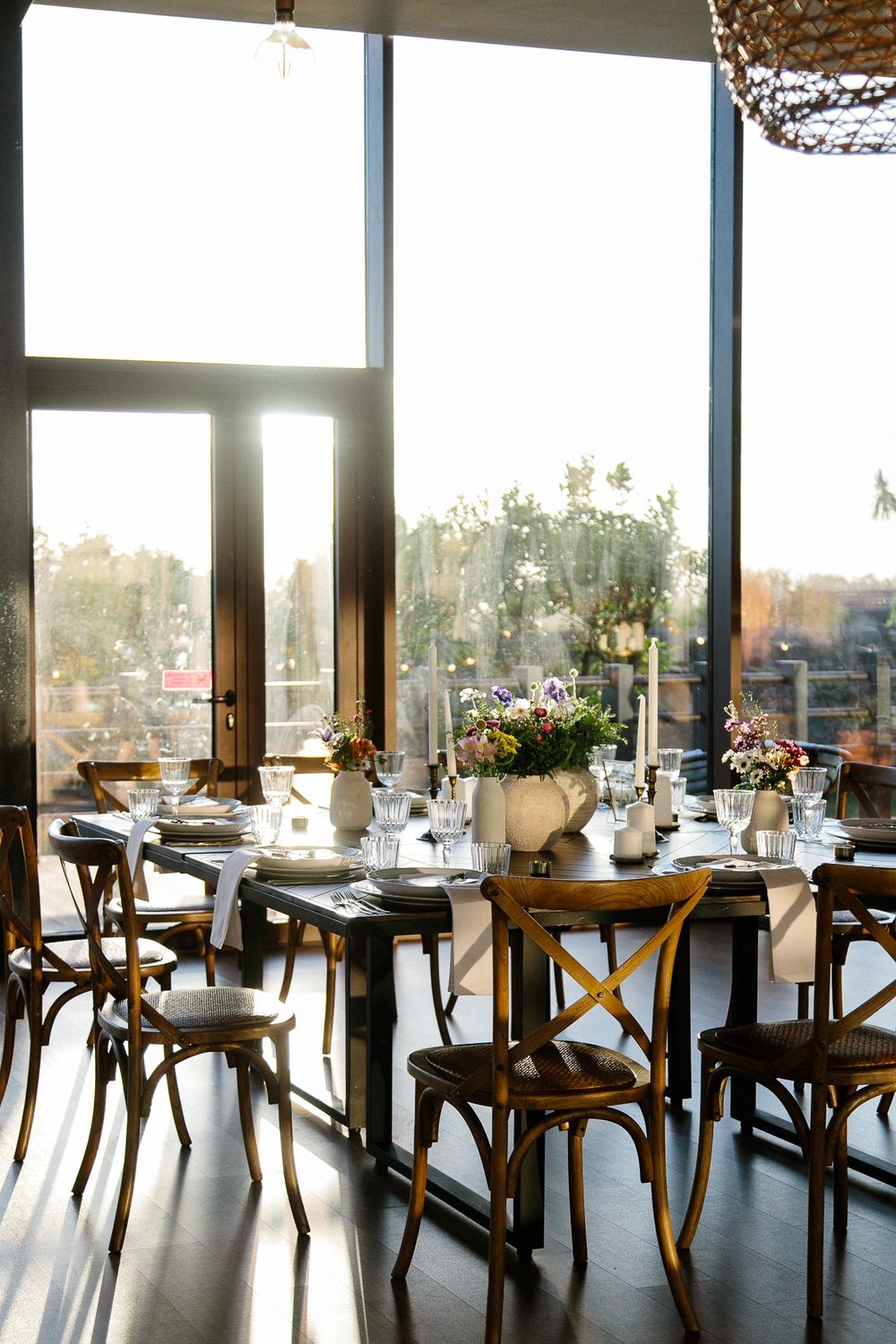 Modern reception venue with elegant table settings and large windows letting in natural light.