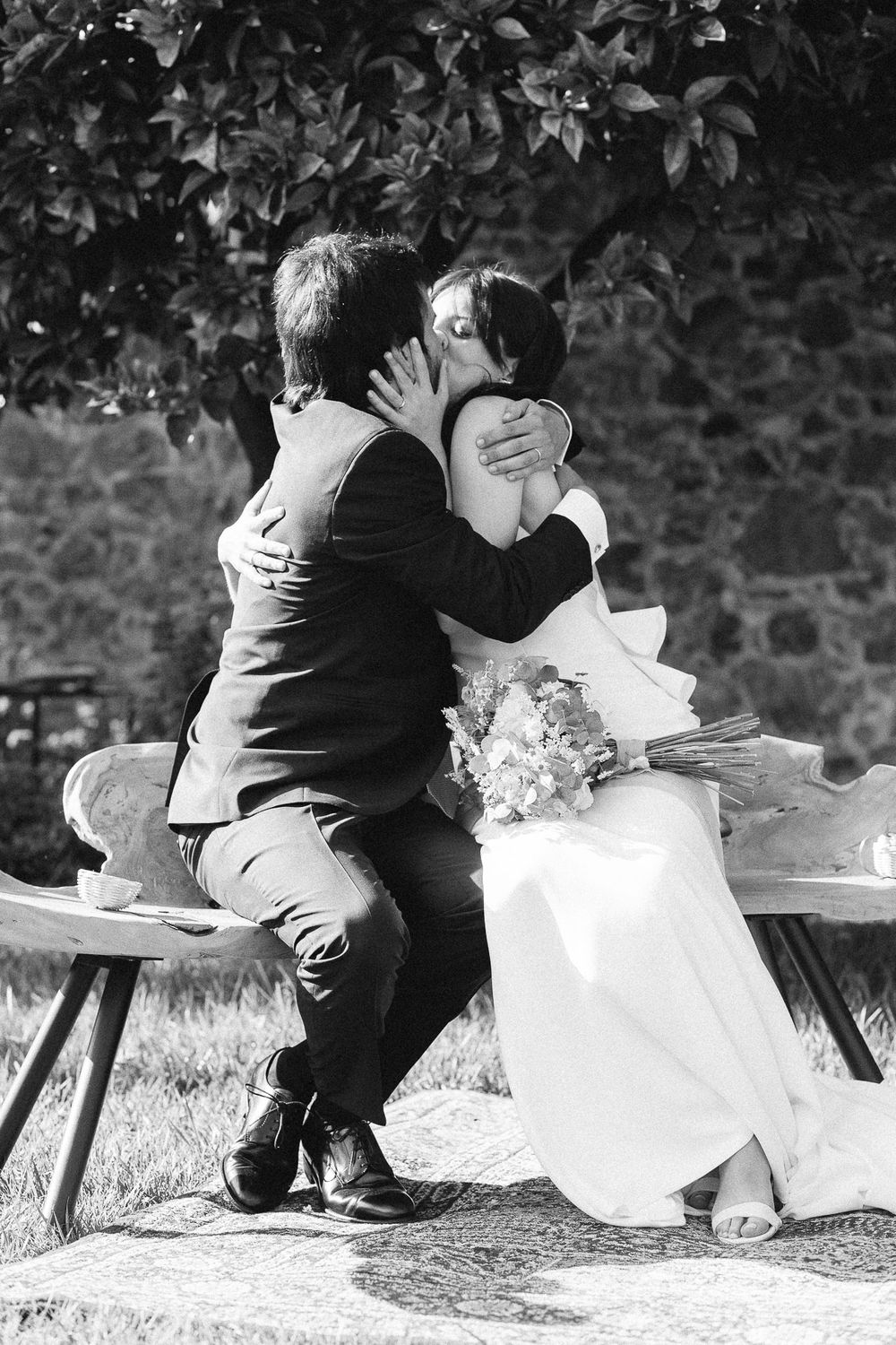 A romantic black and white portrait of a couple sharing an intimate moment on a bench.