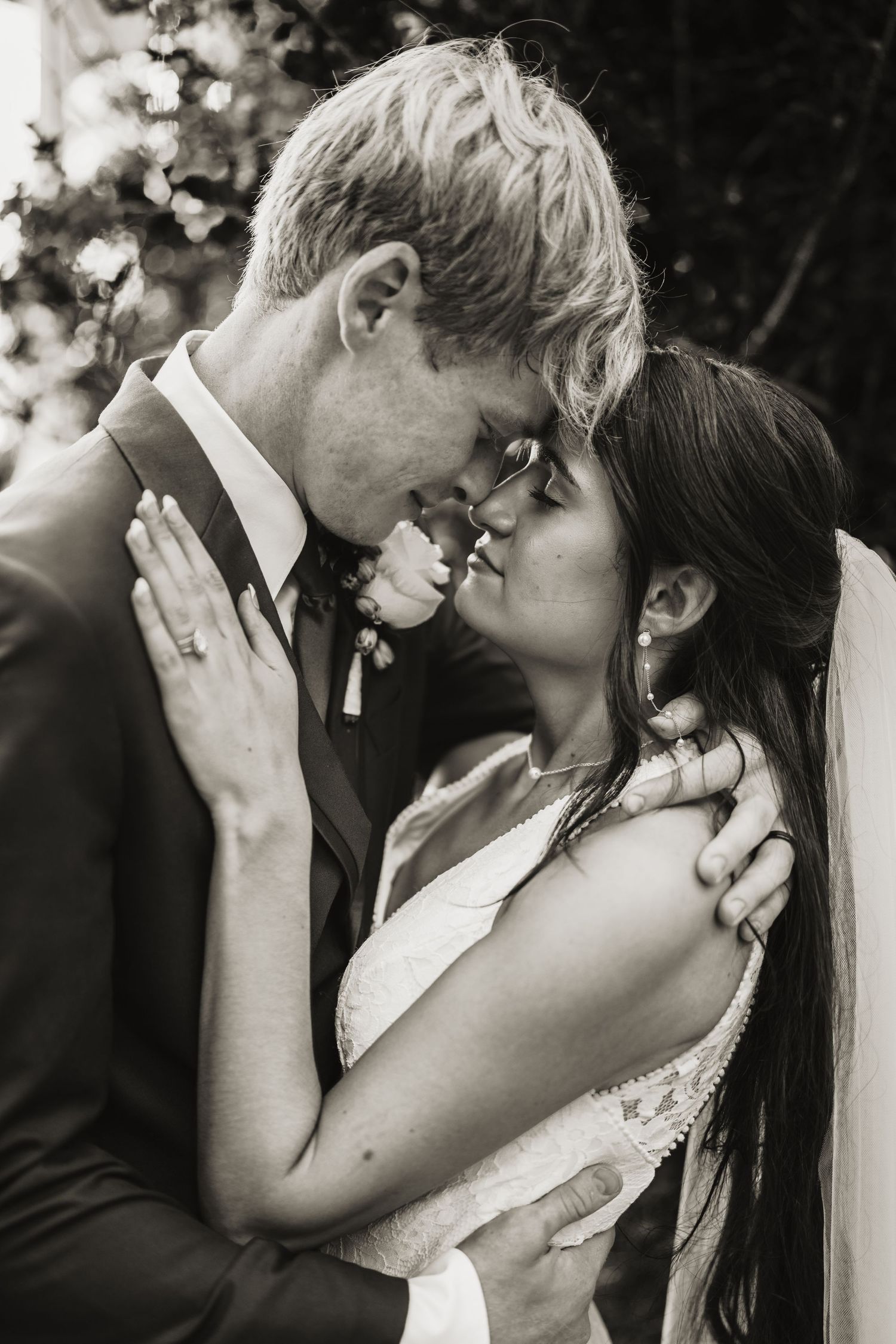 Intimate black and white portrait of newlyweds sharing a tender moment during their wedding.