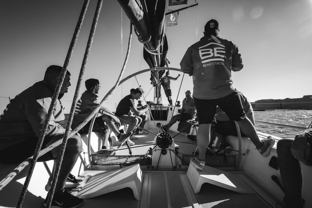 Black and white photo of sailing crew working on sailboat deck during competitive ocean race.