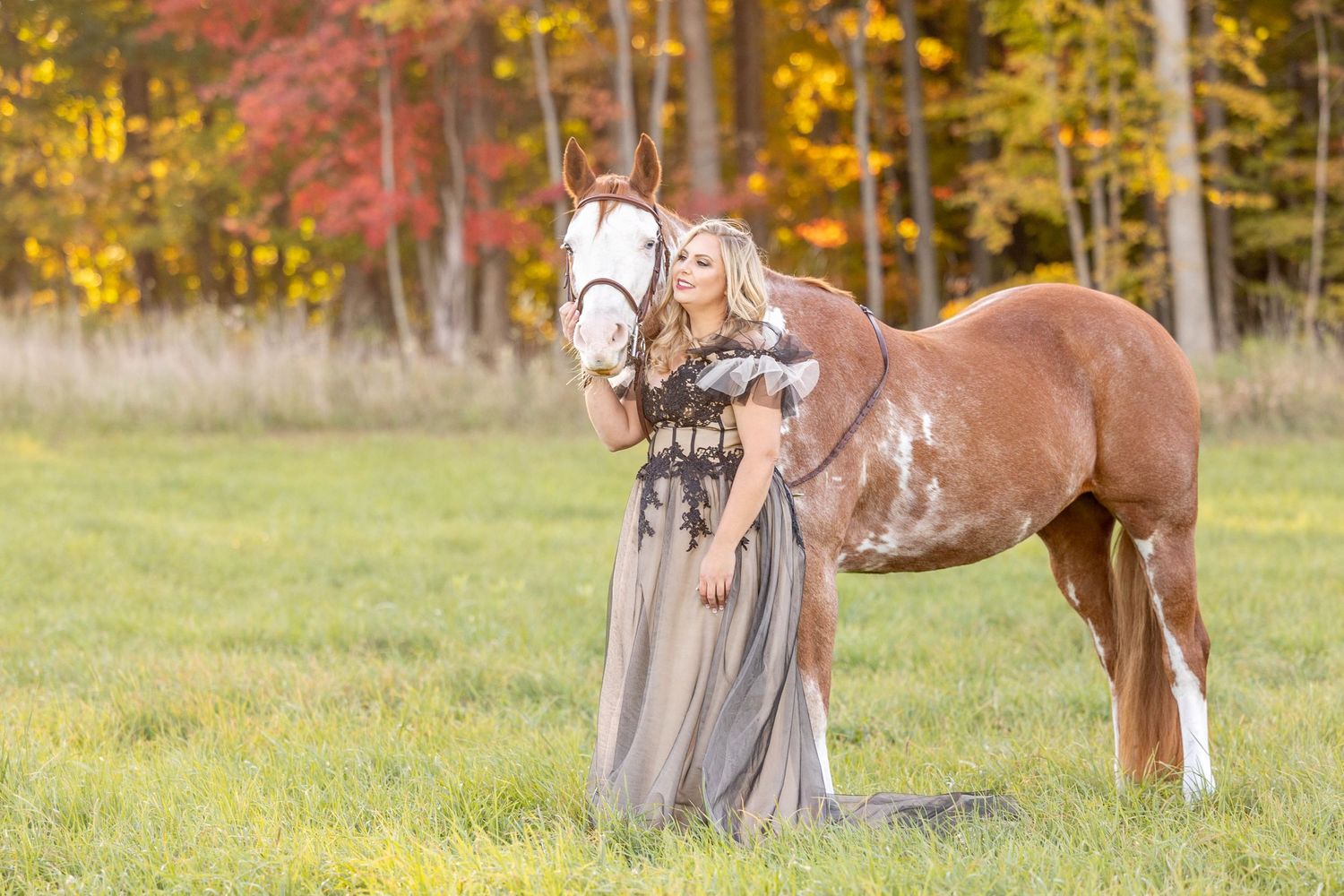 Girl in flowy dress with her paint mare in a field in the fall