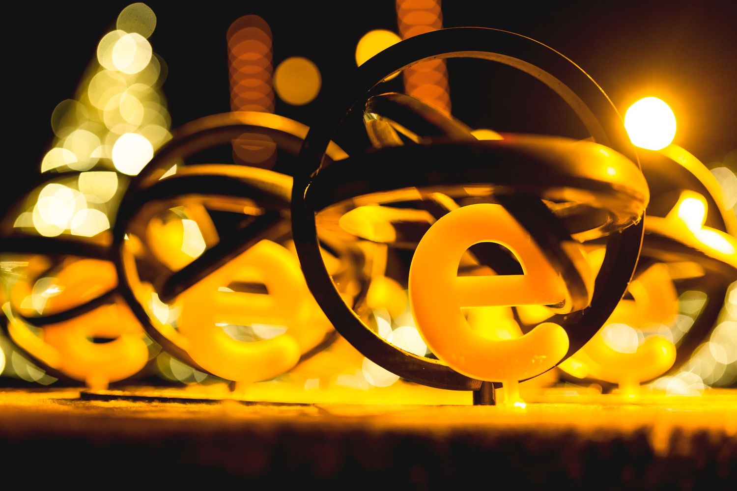 Black eyeglasses frame silhouetted against blurred yellow bokeh lights in the background.